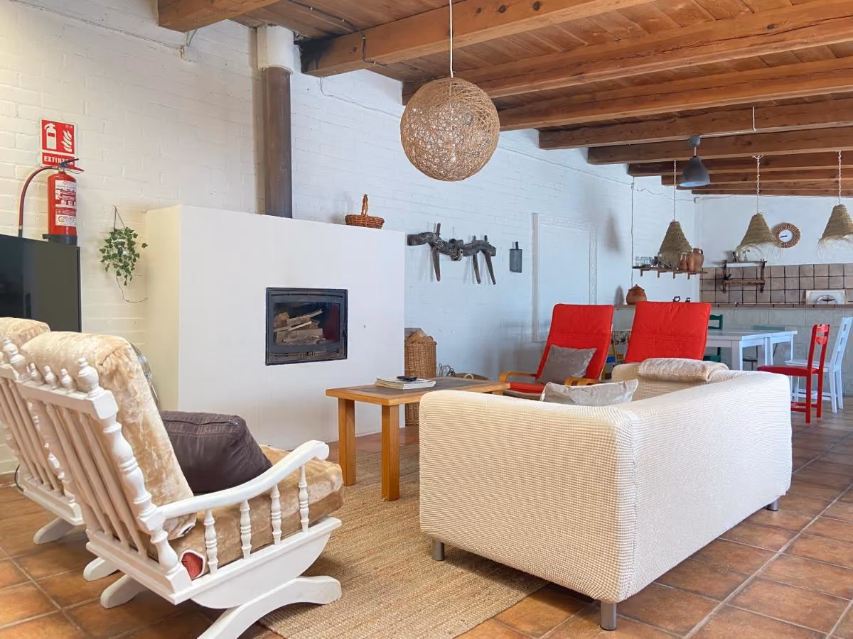Merendero amplio con vigas de madera, chimenea, sofá y mecedora